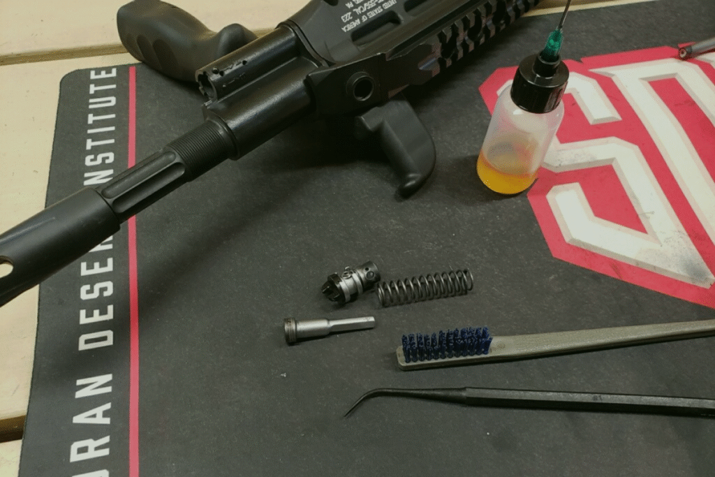 Gunsmithing tools and accessories, including a gas block for the STG, cleaning brush, lubricant bottle, and various components on a work mat.
